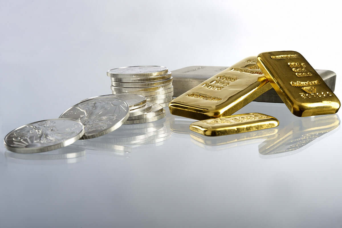 Stacks of silver coins and gold bars placed on a reflective surface, symbolizing wealth, investment, and precious metals trading.