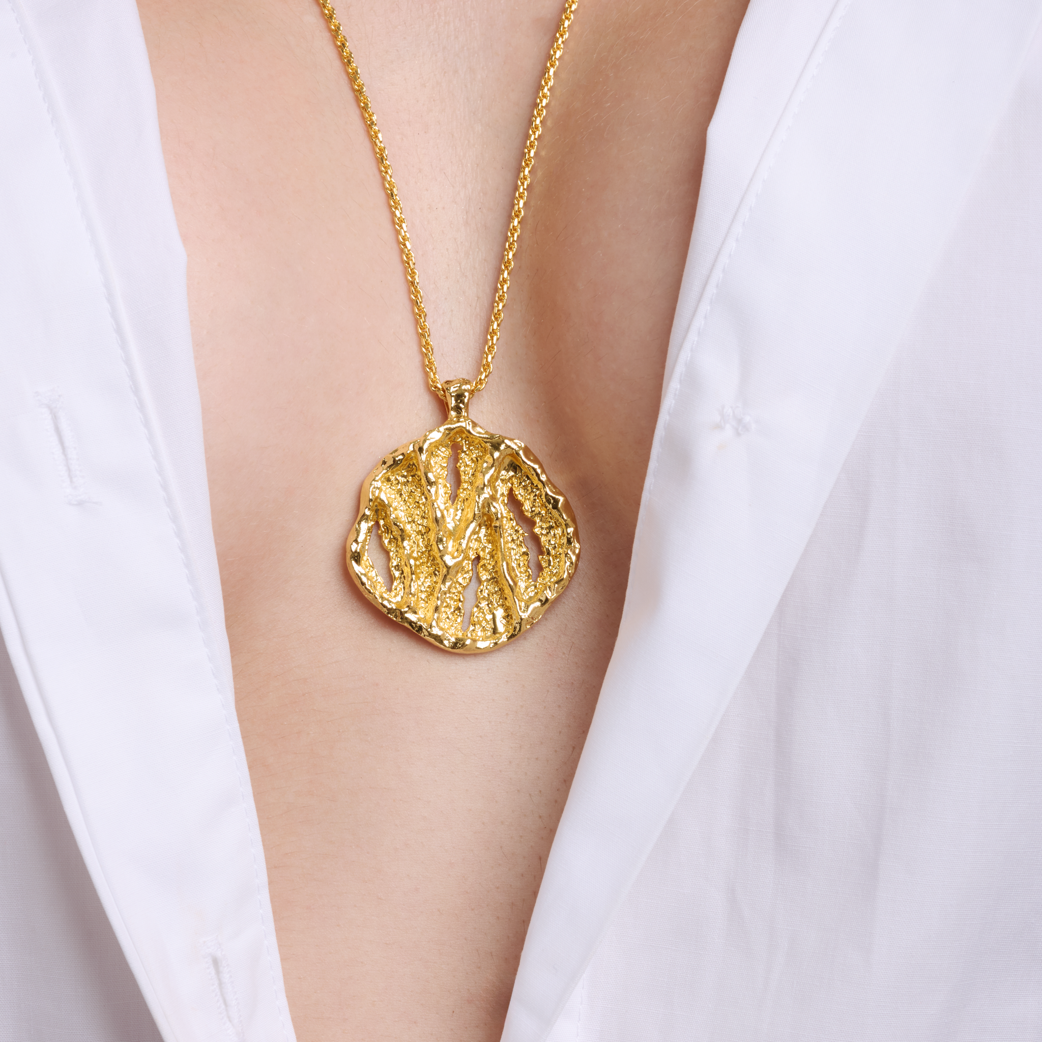 Embrell Becoming Aura Pendant Necklace in 22K gold-plated finish, handcrafted molten textured round pendant on a fine chain, demi-fine jewellery styled with a white shirt for a modern elegant look.