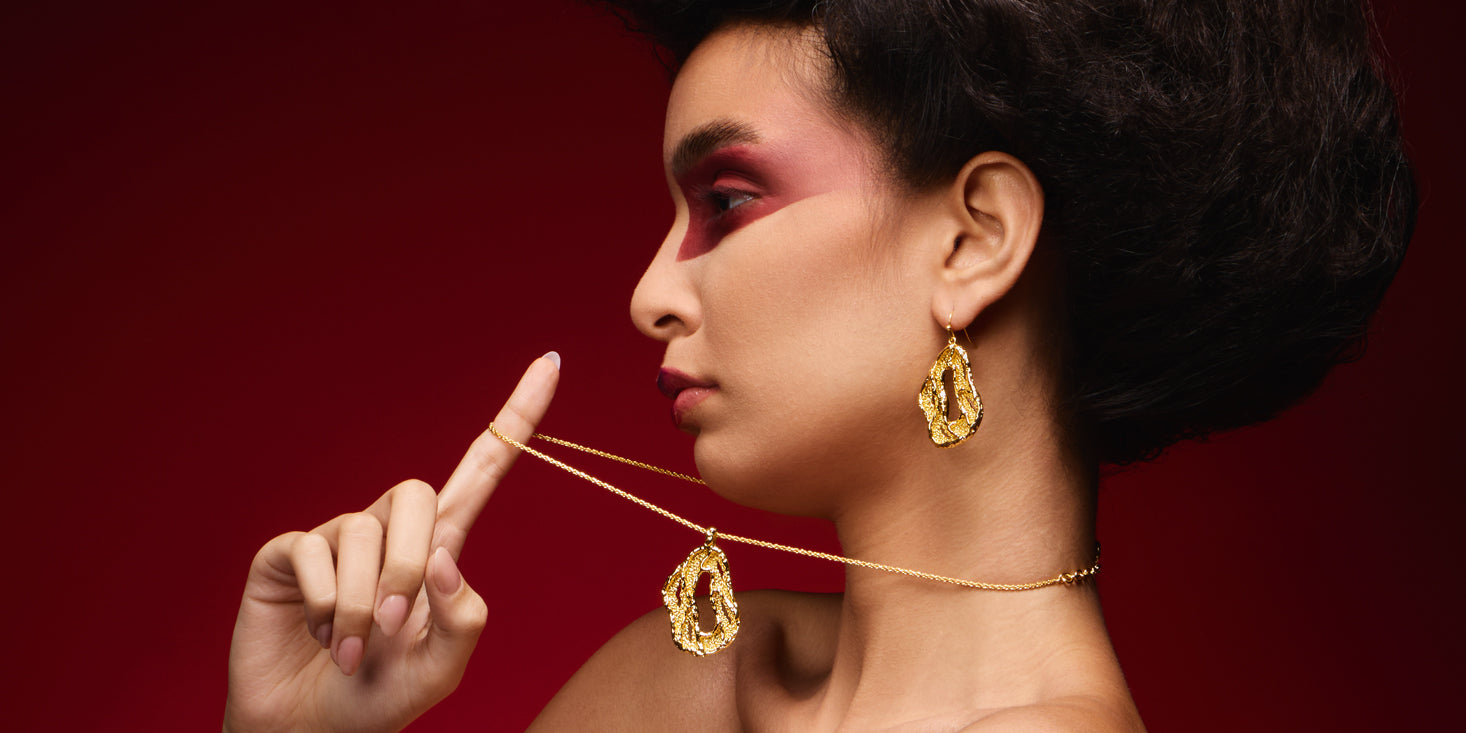 Woman wearing 22k gold jewellery against a red background