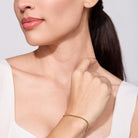 Woman wearing a gold bracelet on a plain background
