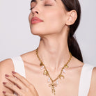 Woman wearing a gold necklace with pearls on a plain background