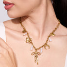 Gold necklace with ribbon charms worn by women on a neutral background
