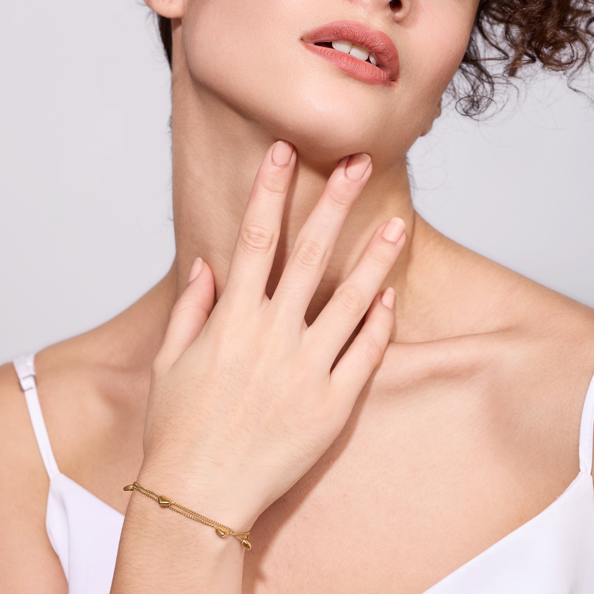 Woman wearing a gold bracelet on a plain background