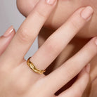 Gold ring on a finger with a neutral background