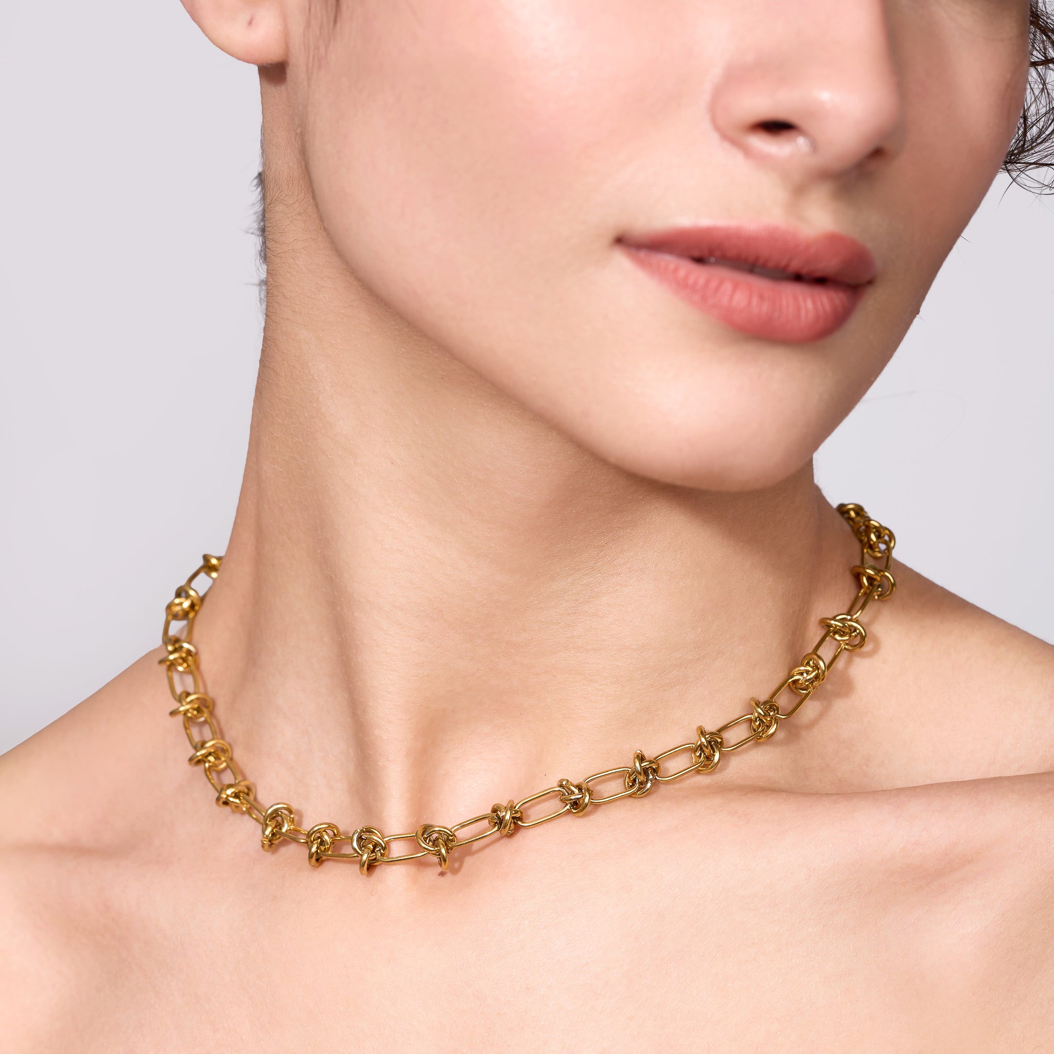 Gold chain necklace on a model against a neutral background