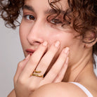 Woman wearing a gold ring on her finger with a neutral background