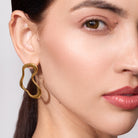 Close-up of a woman wearing a gold earring against a neutral background