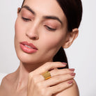 Woman wearing a 18K gold plated ring on a plain background