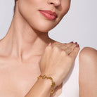 Close-up of a woman's hand wearing a gold bracelet on a light background