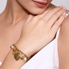 18K gold plated bracelet with charms on a person's wrist against a neutral background.