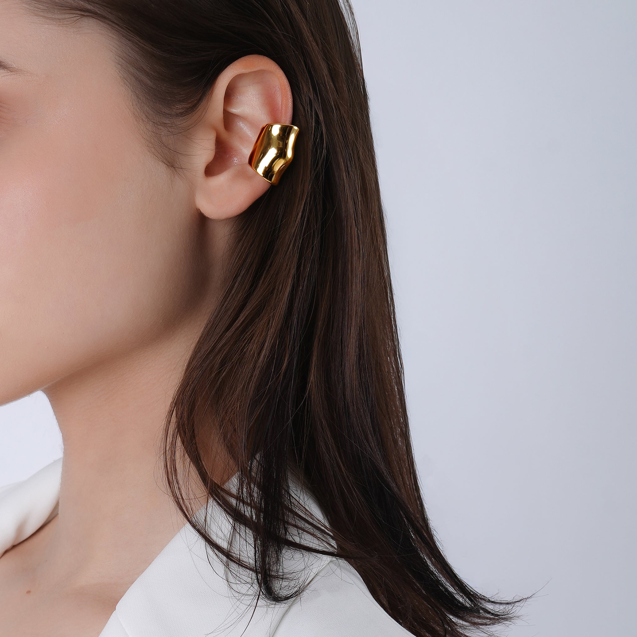 A model wearing 18K gold plated ear cuffs, styled in a sleek and modern fashion, accentuating the ear with a bold and elegant touch