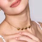 Gold heart-shaped necklace worn by a women with a neutral background