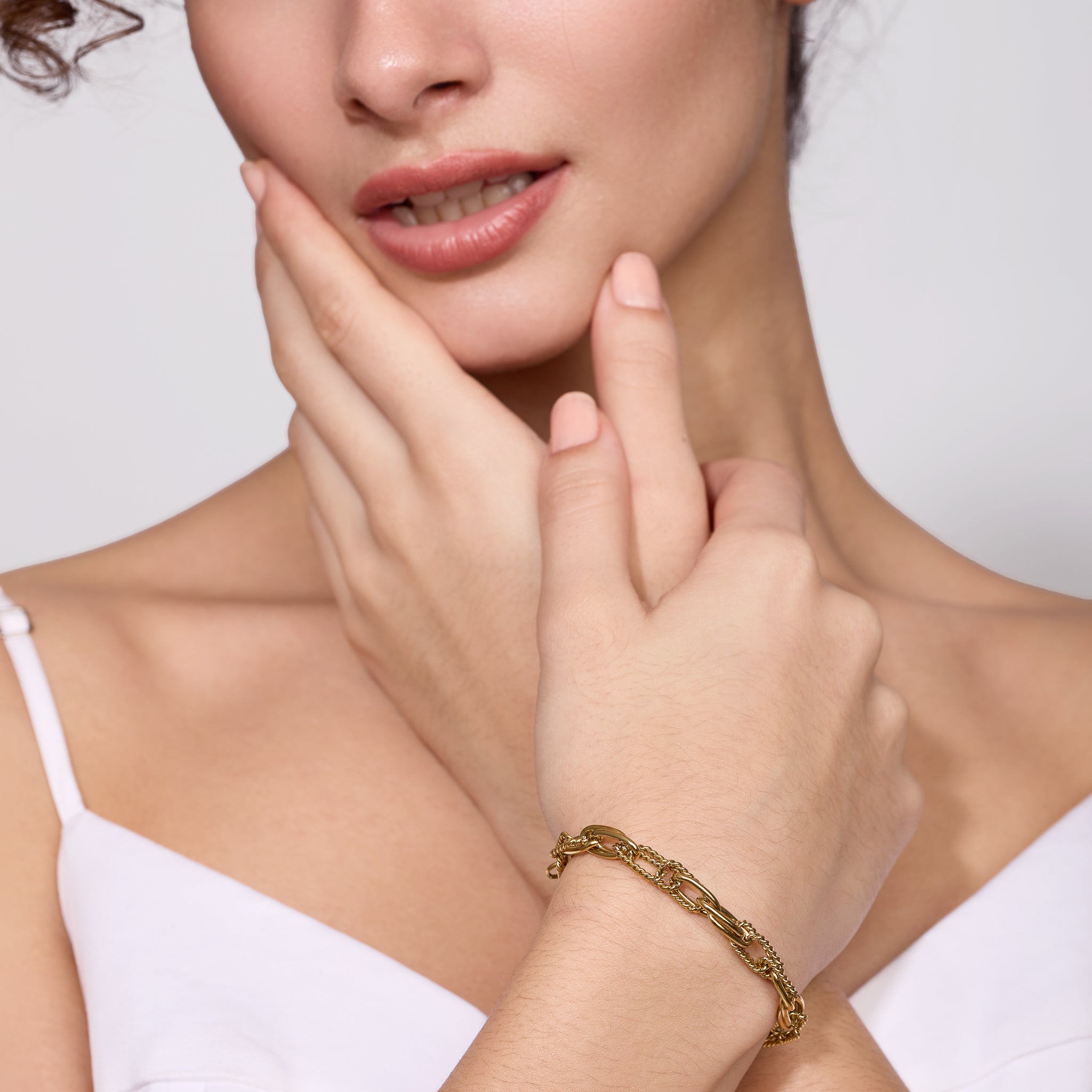 Woman wearing a gold bracelet on a plain background