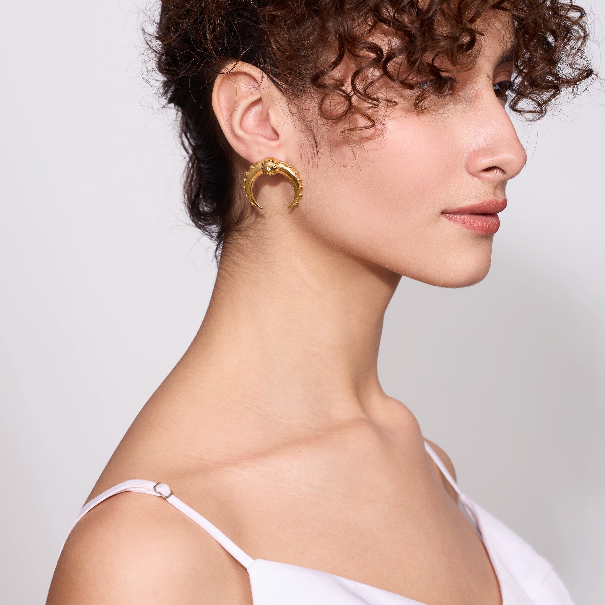 Woman wearing gold hoop earrings with a plain background