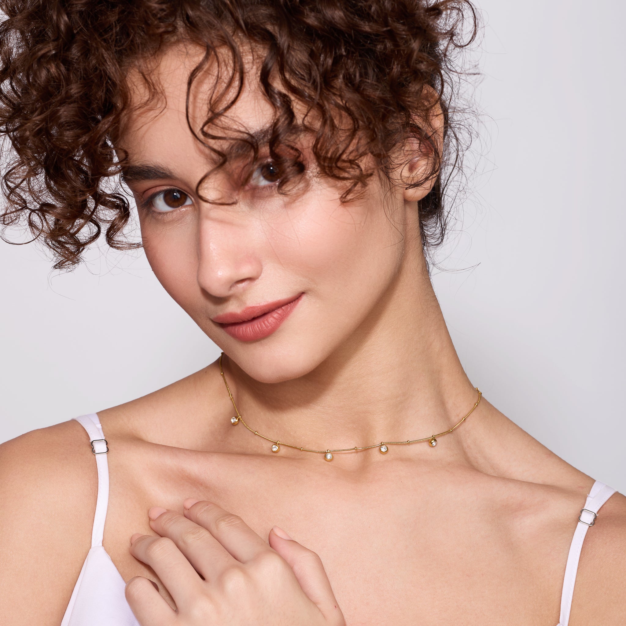 Woman wearing a delicate gold necklace against a plain background
