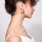 Woman wearing gold hoop earrings with a plain background