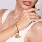 Gold bracelet with charms on a women wrist against a white background