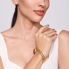 Woman wearing a gold bracelet on a plain background