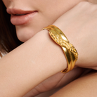 Embrell Becoming Grace Cuff in 22K gold-plated finish, handcrafted molten textured sculptural cuff with intertwined design, demi-fine jewellery worn by a woman for an elegant bold look.