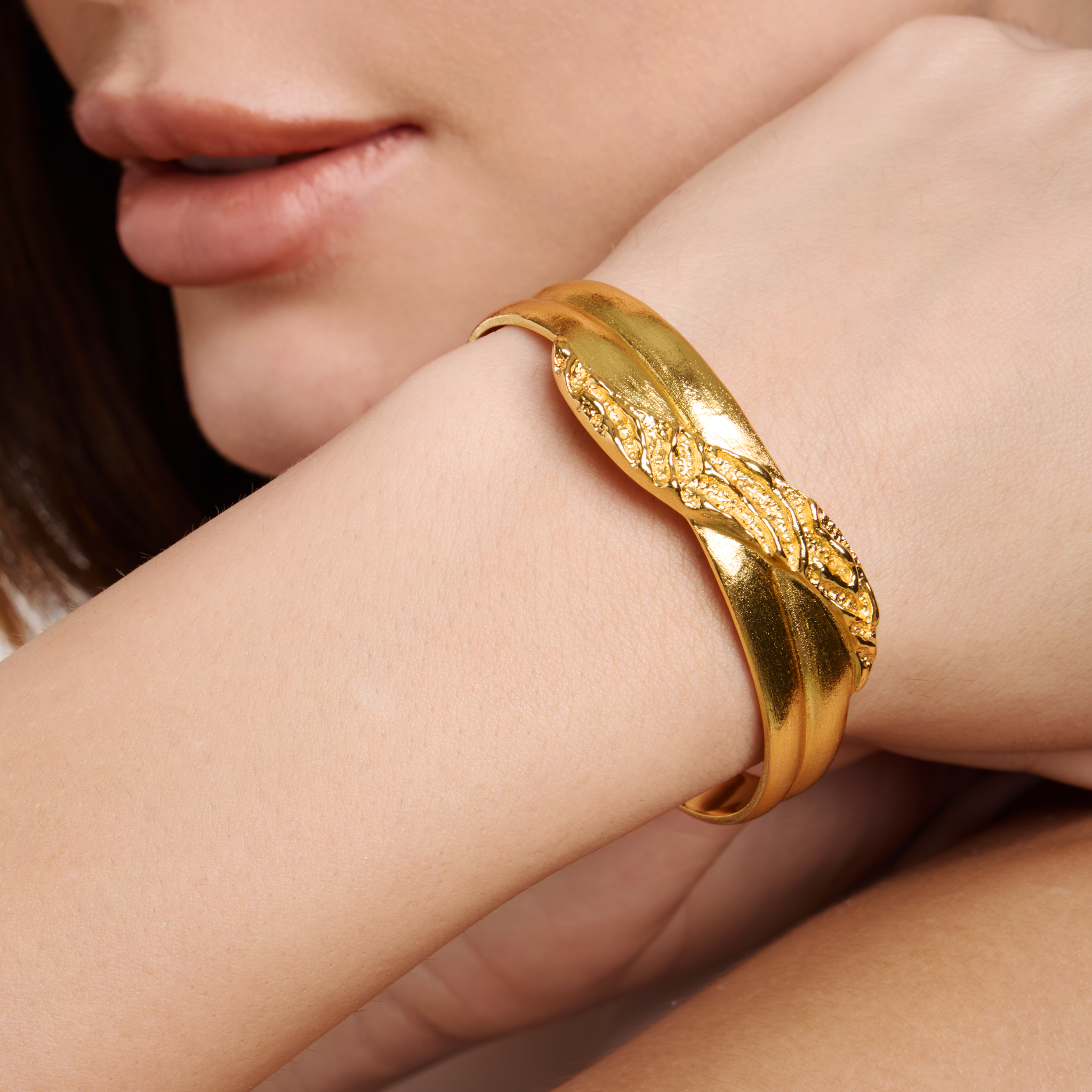 Embrell Becoming Grace Cuff in 22K gold-plated finish, handcrafted molten textured sculptural cuff with intertwined design, demi-fine jewellery worn by a woman for an elegant bold look.