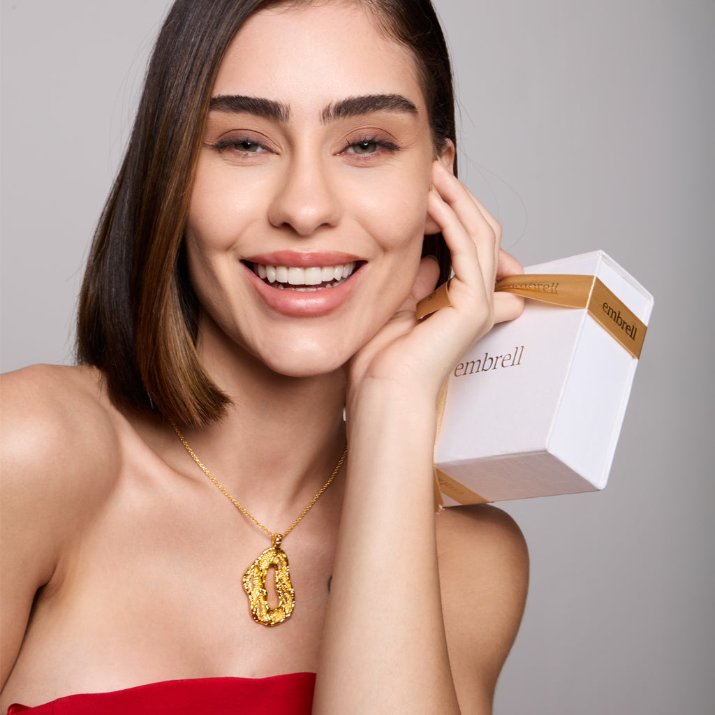 Woman holding a embrell elegance box branding against a gray background