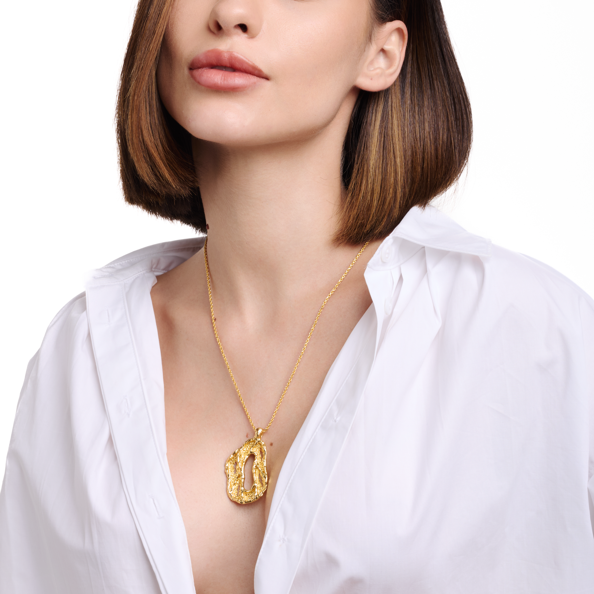 Embrell Becoming Lumen Pendant Necklace in 22K gold-plated finish, handcrafted molten textured open pendant on a fine chain, demi-fine jewellery styled with a white shirt for an elegant bold look.
