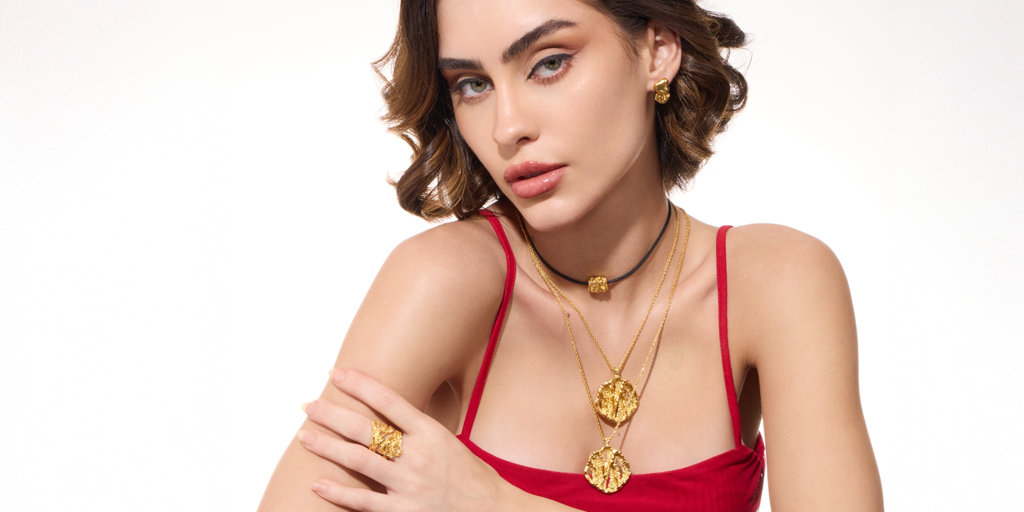 Woman wearing 22k gold plated necklaces and earrings on a white background