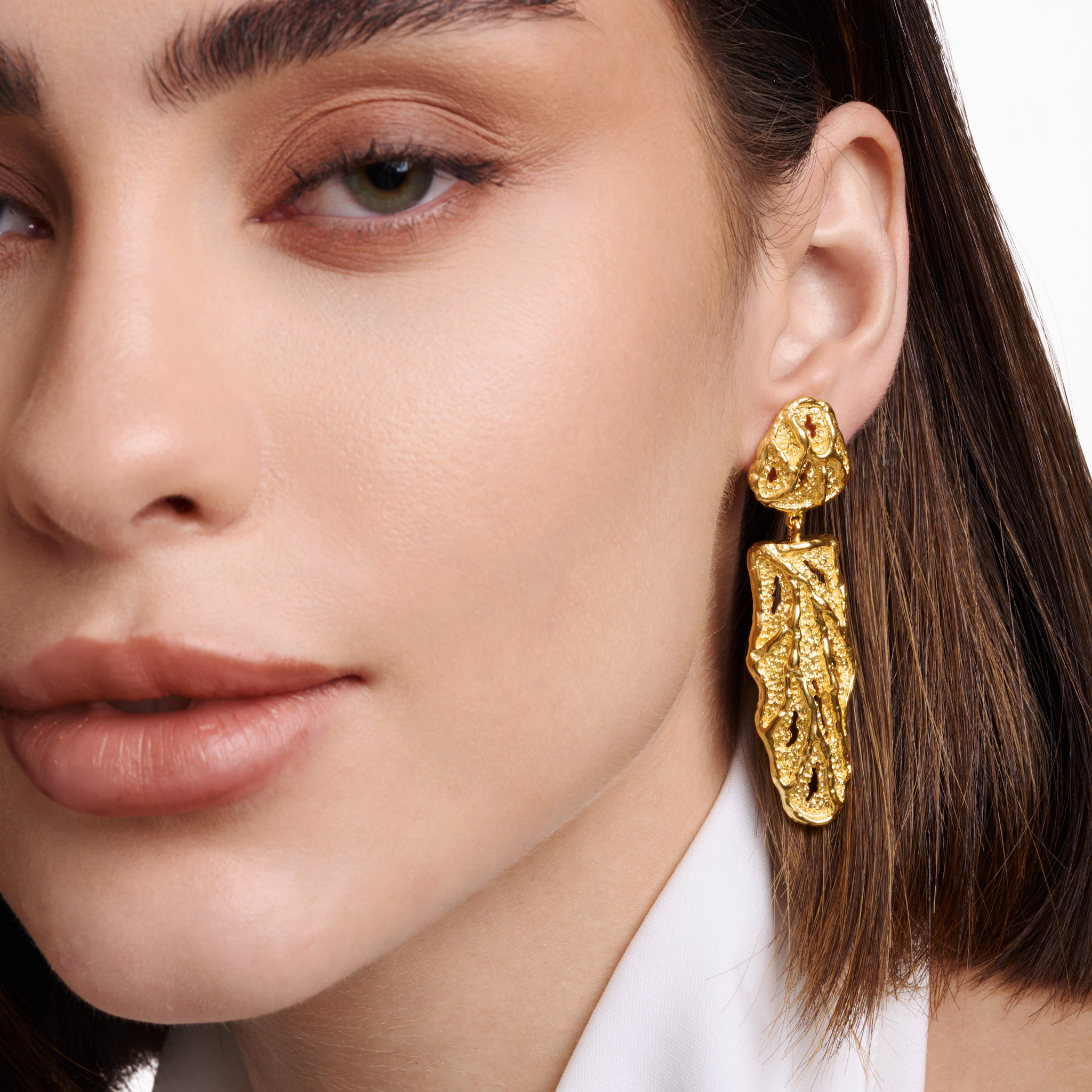 Embrell Becoming Reign Earrings in 22K gold-plated finish, molten textured statement drop earrings, handcrafted demi-fine jewellery, worn by a woman for a bold elegant look.