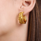 Embrell Becoming Rise Hoop Earrings in 22K gold-plated finish, handcrafted demi-fine molten textured gold hoops, worn by a woman for a modern elegant look.
