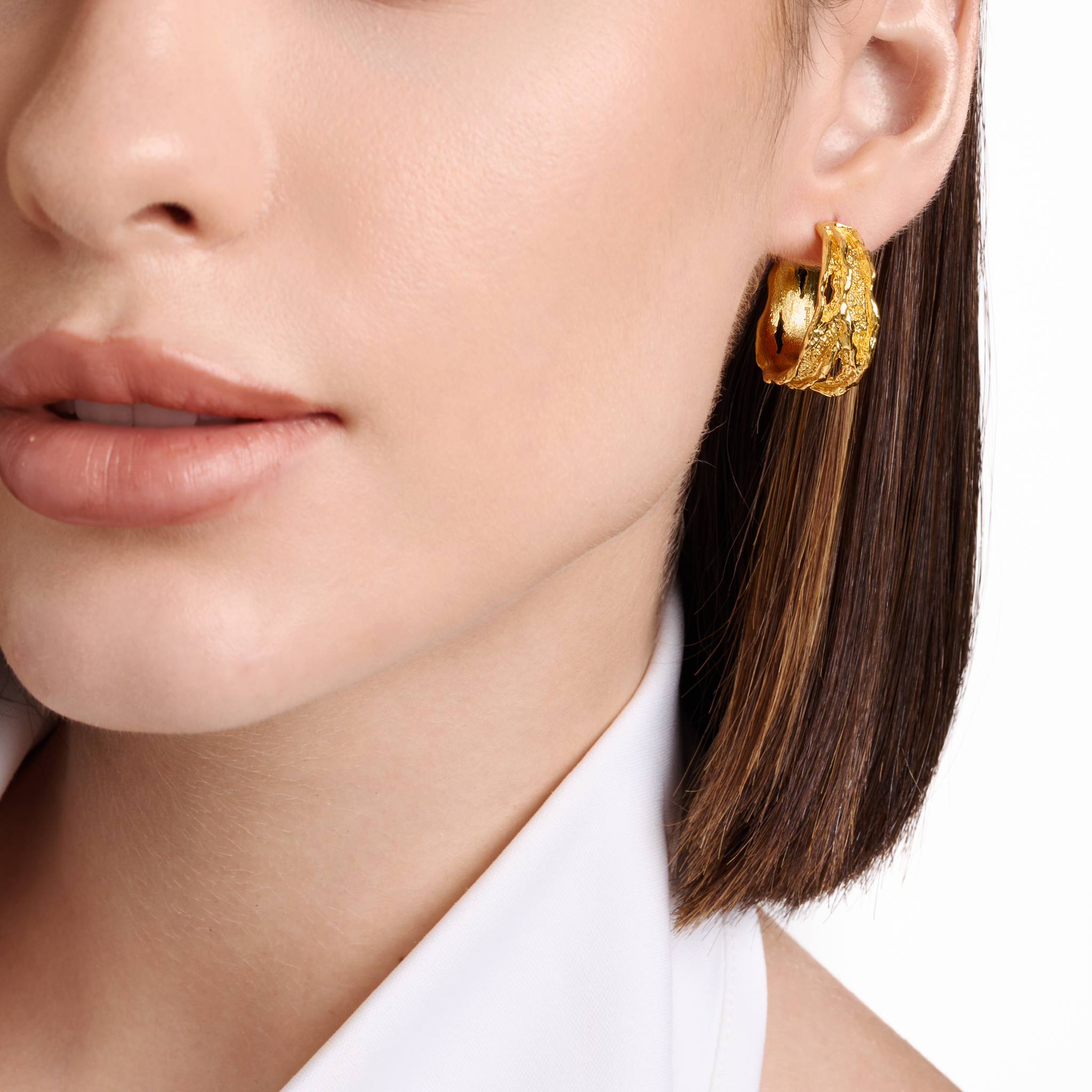 Embrell Becoming Rise Hoop Earrings in 22K gold-plated finish, handcrafted demi-fine molten textured gold hoops, worn by a woman for a modern elegant look.
