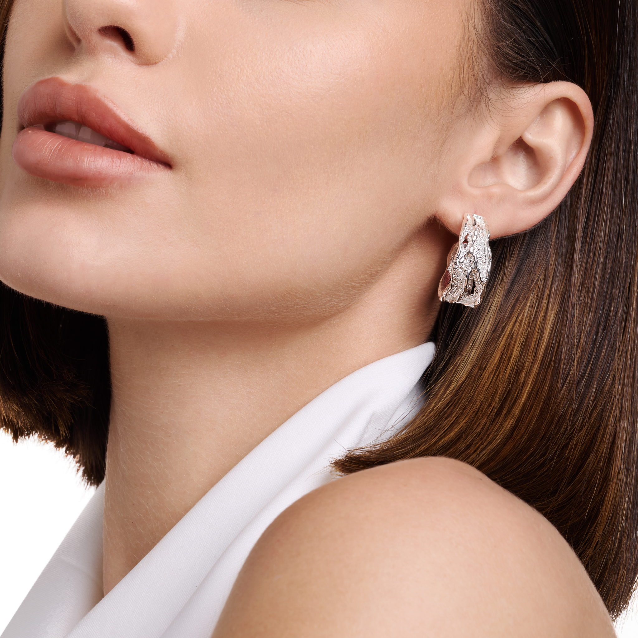 Embrell Becoming Rise Hoop Earrings in silver rhodium-plated finish, handcrafted demi-fine molten textured hoops, worn by a woman for a modern elegant look.