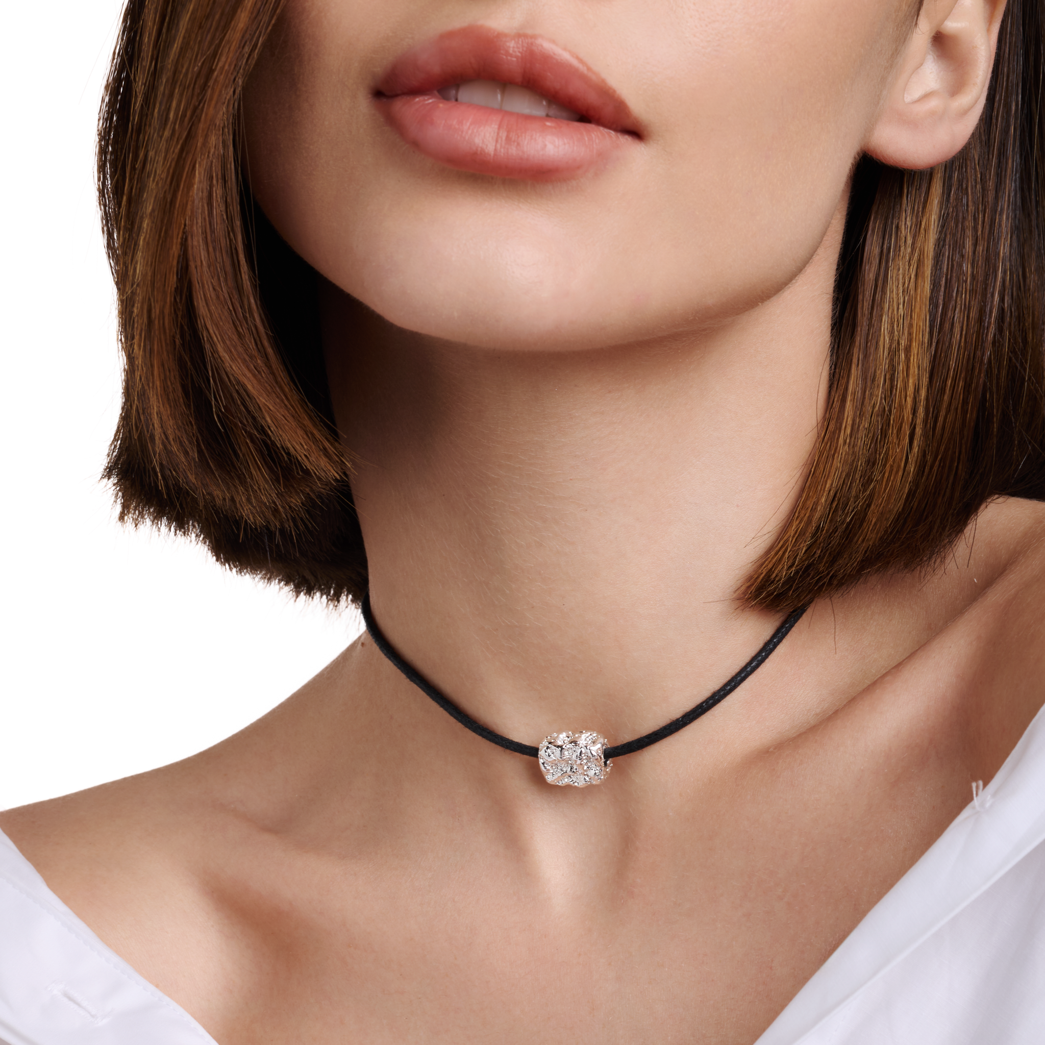 Embrell Becoming Talisman Necklace in silver rhodium-plated finish, handcrafted molten textured pendant on a black choker cord, demi-fine jewellery worn by a woman styled with a white shirt for a modern elegant look.